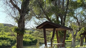 Ein Pavillon in einer natürlichen Umgebung, umgeben von Gras und Pflanzen, in der Nähe von Wasser.