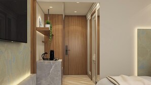 A modern hotel room with a large flat-screen TV, a marble accent wall, a wooden door, and a bed with a beige blanket. - Goldfinch Panjim Goa (Panaji)