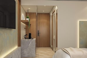 Un dormitorio moderno con una cama grande, un televisor montado en la pared, una puerta de madera y una pequeña zona de cocina con cafetera.