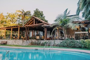 A poolside area with outdoor seating and a stone wall. - Hotel Fundo Las Tórtolas (Limache)