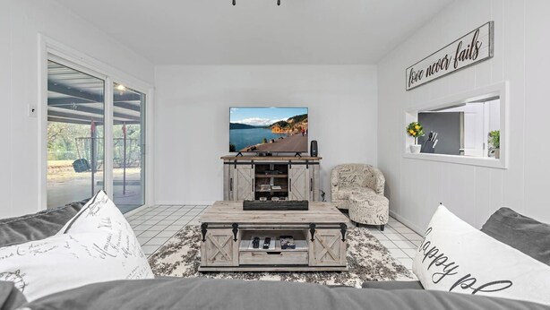Una sala de estar con televisor, mesa de centro, sofá y sillón.