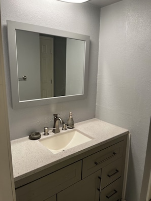 A bathroom with a white sink, a mirror, and a cabinet with drawers. - 3-bedroom townhome in fantastic Kansas City with AC (Kansas City)