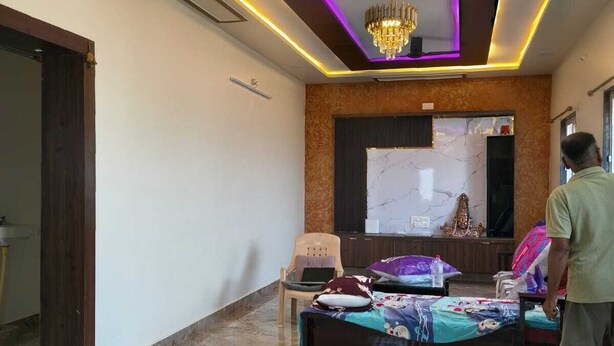 Una habitació amb un llit, una cadira, un ventilador de sostre i una làmpada penjant.