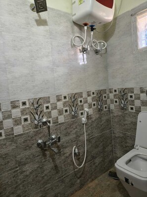 Ein Badezimmer mit Dusche, Toilette und Durchlauferhitzer.