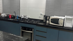 A modern kitchen with a black marble countertop, stainless steel appliances, and blue cabinets. - Beautiful and cozy duplex with private pool. (Guarujá)