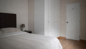 A bedroom with a bed, a nightstand, a lamp, and a wardrobe. - Modern, comfortable and centrally located apartment (Lima)