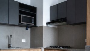 A modern kitchen with dark cabinets, a microwave, a gas stove, and a wooden countertop. - Modern, comfortable and centrally located apartment (Lima)