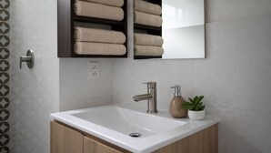 A bathroom with a white sink, a modern faucet, and a shelf with neatly folded towels. - Modern, comfortable and centrally located apartment (Lima)