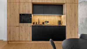 Une cuisine moderne avec des meubles en bois, un plan de travail noir et un four encastré.