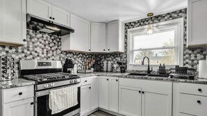 A modern kitchen with white cabinets, a stainless steel stove, and a black countertop.