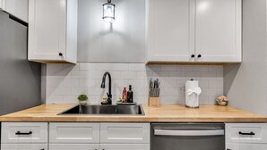 Uma cozinha moderna com armários brancos, pia de aço inoxidável e espaço para lavar louça.