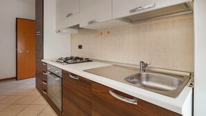 Eine moderne Küche mit Spüle aus Edelstahl, Holzschränken und einem Gasherd.