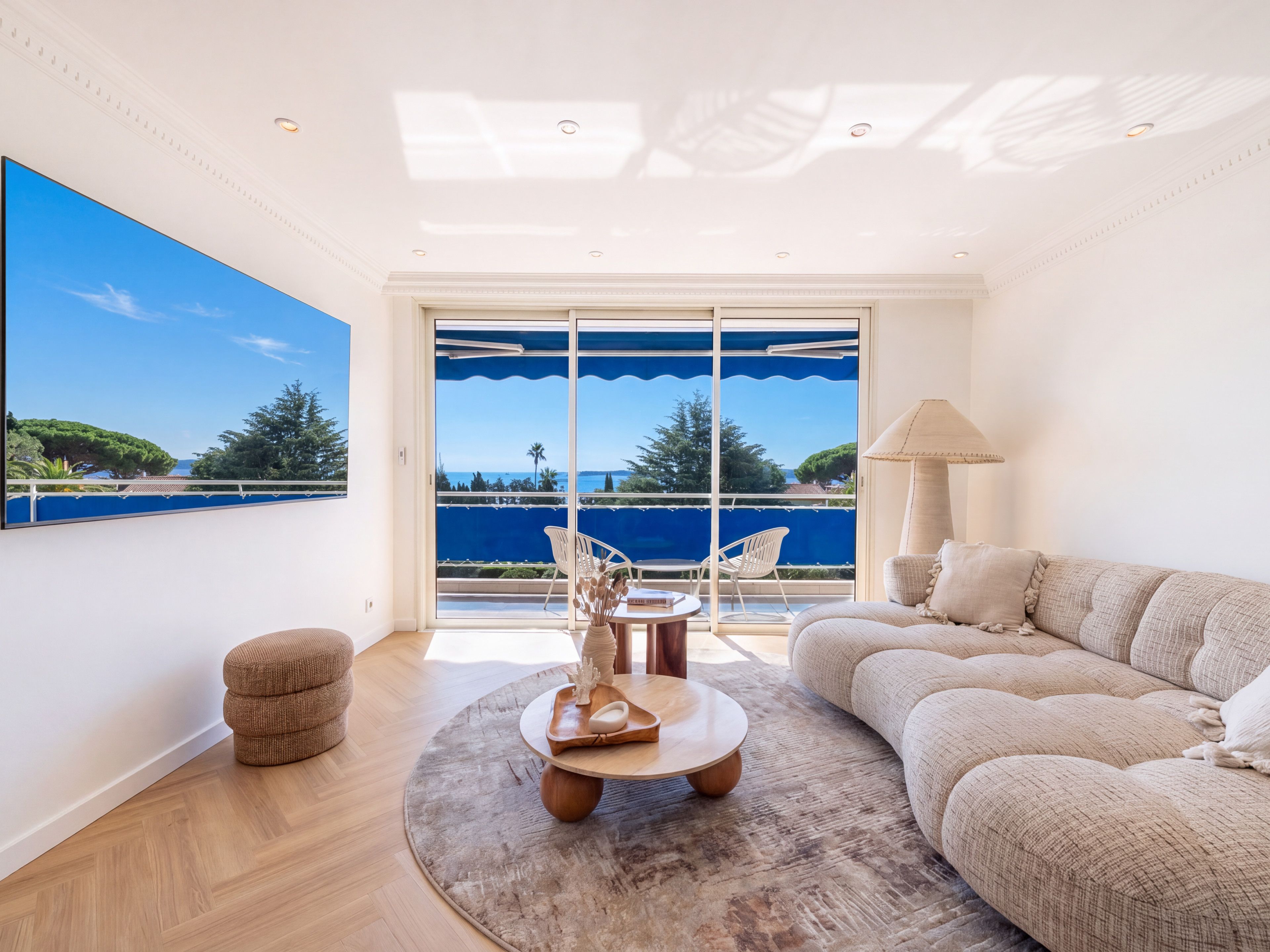 A spacious living room with a large window, a sofa, a coffee table, and a view of the sea.