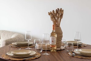 A dining table set with plates, glasses, and a bottle of wine, surrounded by a woven placemat. - 2-Br Sea-View Apartment – East Cannes (Cannes)