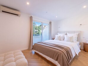 A bedroom with a large bed, a window with curtains, a ceiling fan, and a wall-mounted air conditioner. - 2-Br Sea-View Apartment – East Cannes (Cannes)