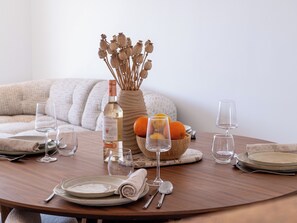 A dining table set with plates, glasses, cutlery, a bottle of wine, and a bowl of fruit. - 2-Br Sea-View Apartment – East Cannes (Cannes)
