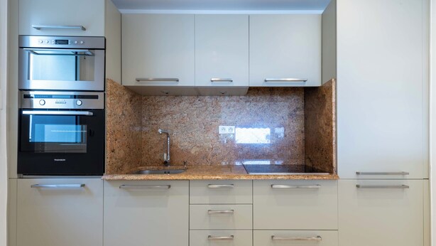 A modern kitchen with built-in appliances, granite countertops, and light-colored cabinetry. - 2-Br Sea-View Apartment – East Cannes (Cannes)