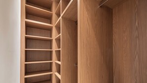 Un placard en bois avec plusieurs étagères et une tringle pour suspendre les vêtements.
