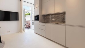 Une cuisine moderne équipée d’un téléviseur à écran plat, d’un four à micro-ondes encastré et d’un plan de travail en granit.