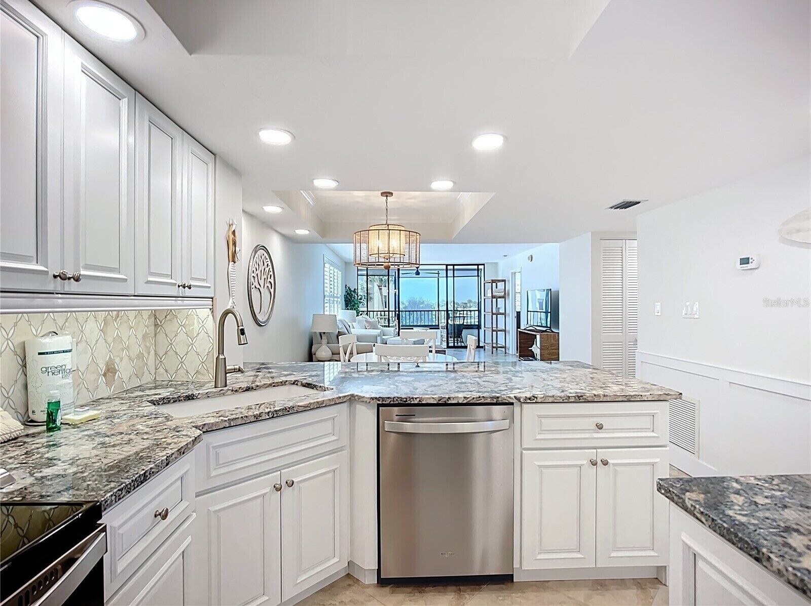 A modern kitchen with white cabinetry, a granite countertop, and a built-in dishwasher.