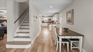 A modern kitchen with white cabinets, a wooden dining table, and a staircase leading to another level. - Sunflower Yellow Coastal Escape (Galveston)
