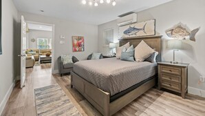 A bedroom with a bed, bedside tables, a nightstand, a lamp, and a wall with a shark painting. - Sunflower Yellow Coastal Escape (Galveston)
