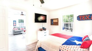 Een slaapkamer met een groot bed, een televisie, een raam en een decoratie met een Texas vlag.