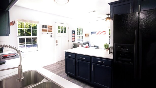 Een moderne keuken met donkere kastjes, een roestvrijstalen spoelbak en een zwarte koelkast.
