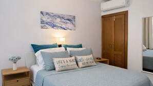 Ein Schlafzimmer mit einem Bett, einem Nachttisch, einem Deckenventilator, einer Wandklimaanlage und einem Holzschrank.