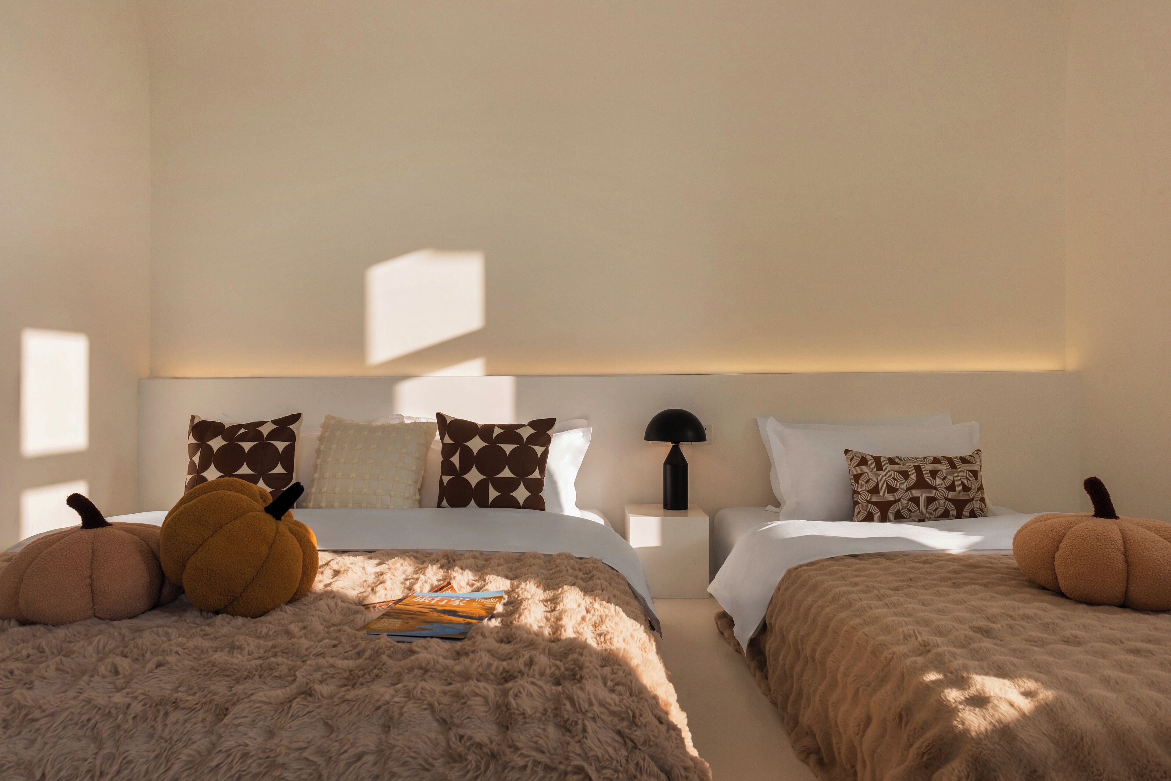 Una camera da letto con due letti, un tappeto morbido e zucche decorative.