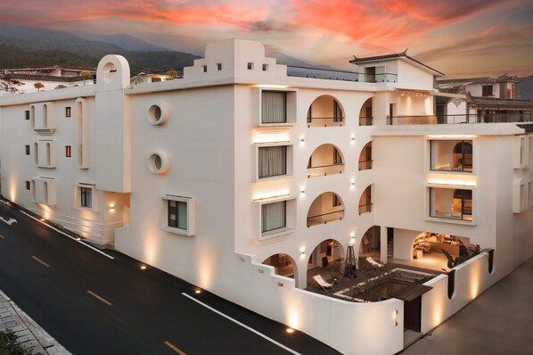 A modern building with multiple balconies, arched windows, and a courtyard with seating. - Mountain Resort Hotel (Dali)