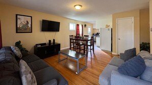 A living room with a TV, sofa, and dining area. - Duke Stayhouse (Durham)