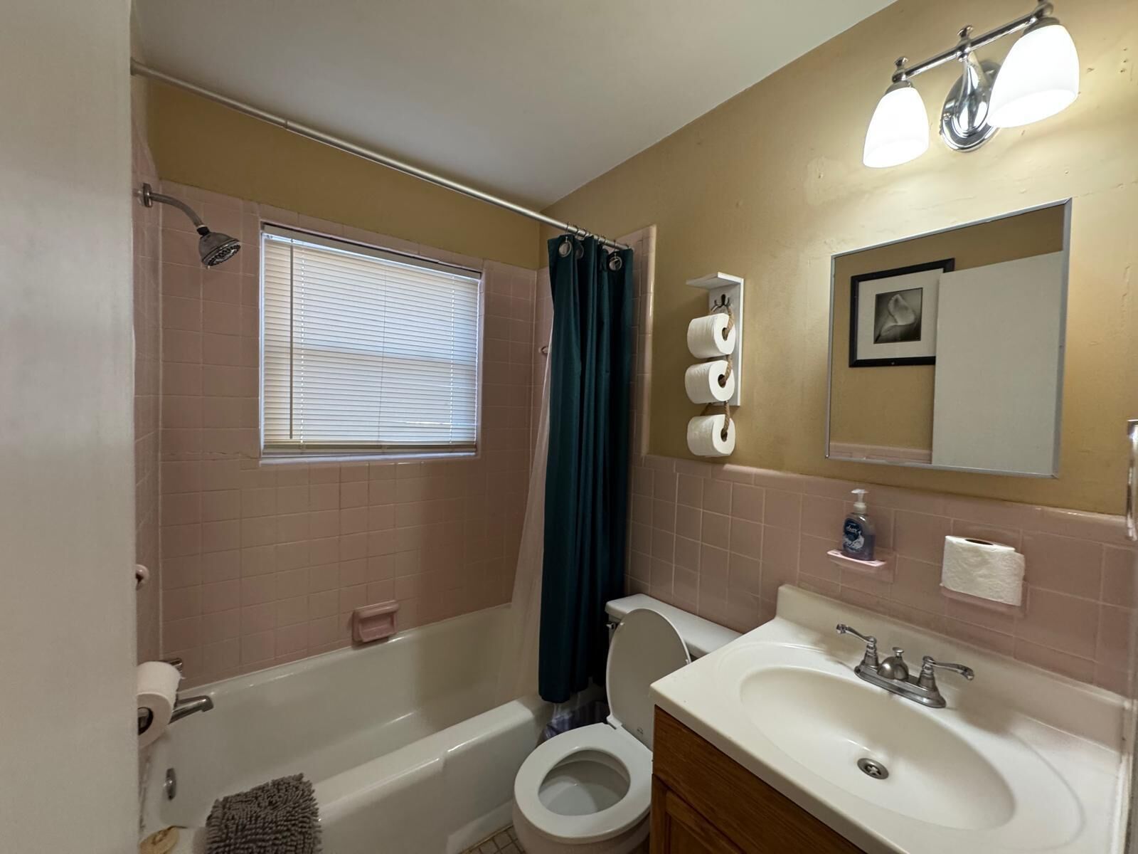 A bathroom with a bathtub, toilet, sink, and a window with blinds.