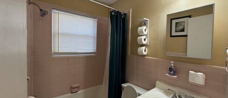 A bathroom with a bathtub, toilet, sink, and a window with blinds.