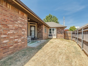 A brick house with a covered patio, a door, and a small window. - Antique and Modern Charming 3-bedroom home, 7 mins to Paycom & Convention Center (Oklahoma City)