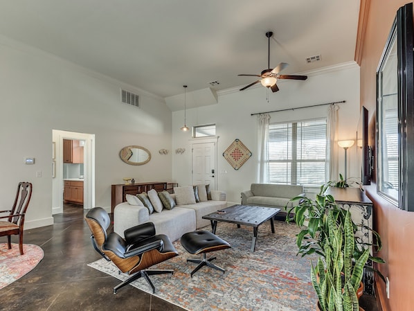 A spacious living room with a ceiling fan, a sofa, a coffee table, and a dining area.