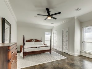 A bedroom with a wooden bed, a ceiling fan, and a large window with blinds.