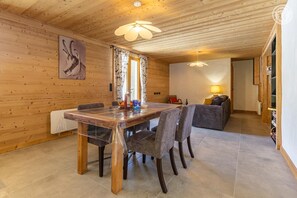 Ein Zimmer mit Holzwänden, einem Esstisch, Stühlen und einer Couch.