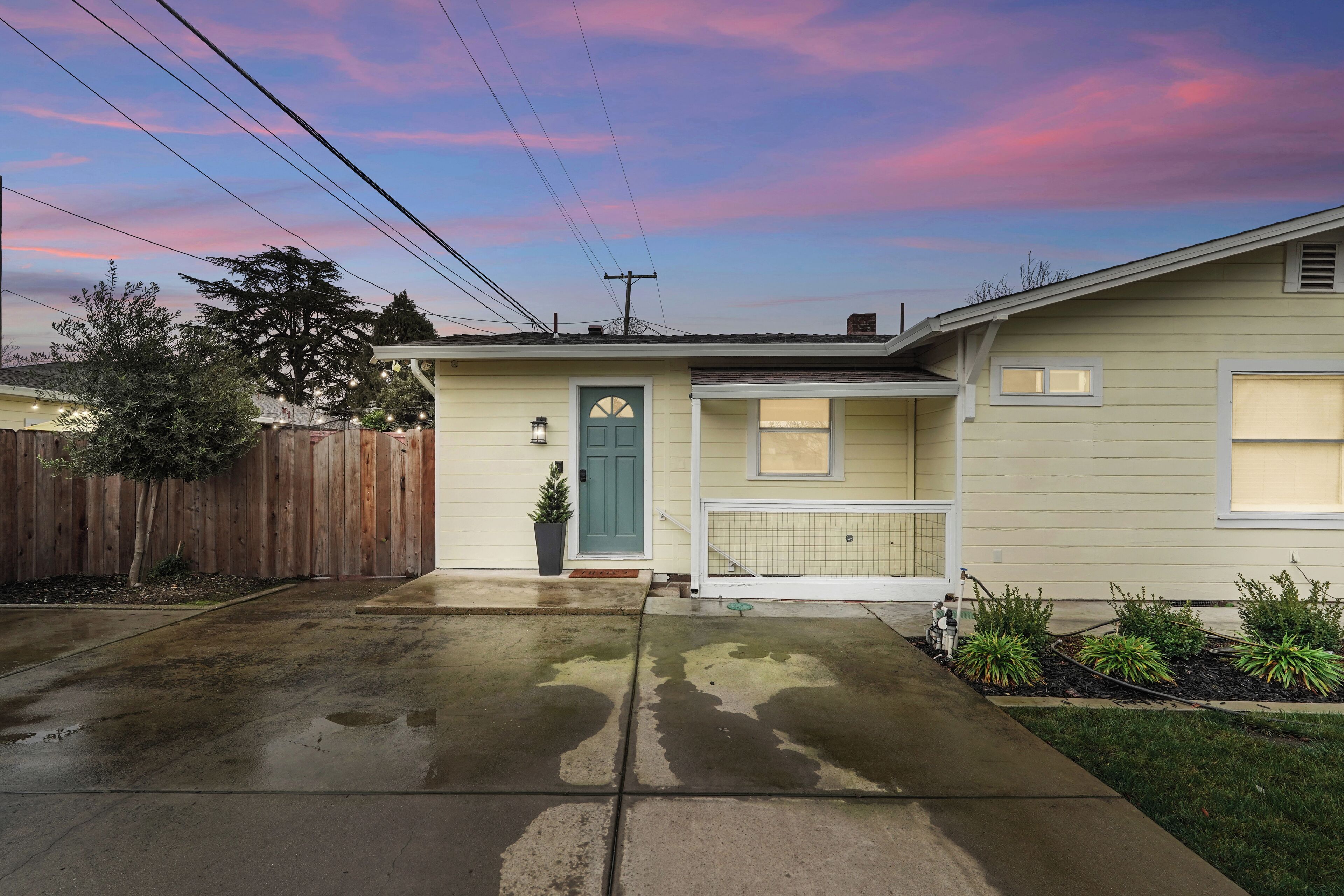 A residential house with a front yard, a wooden fence, and a driveway.