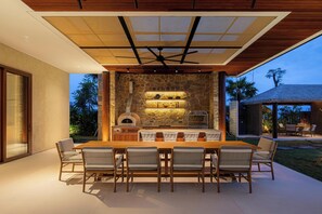 Un área de comedor al aire libre con un muro de piedra de fondo, una mesa de madera y seis sillas.