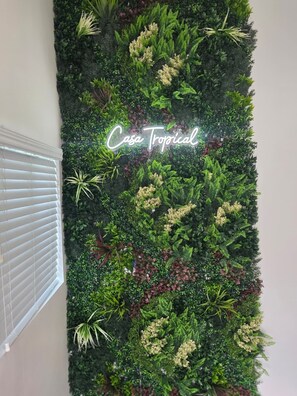 Eine vertikale Begrünung mit einer Neonreklame, die "Casa Tropical" zeigt.