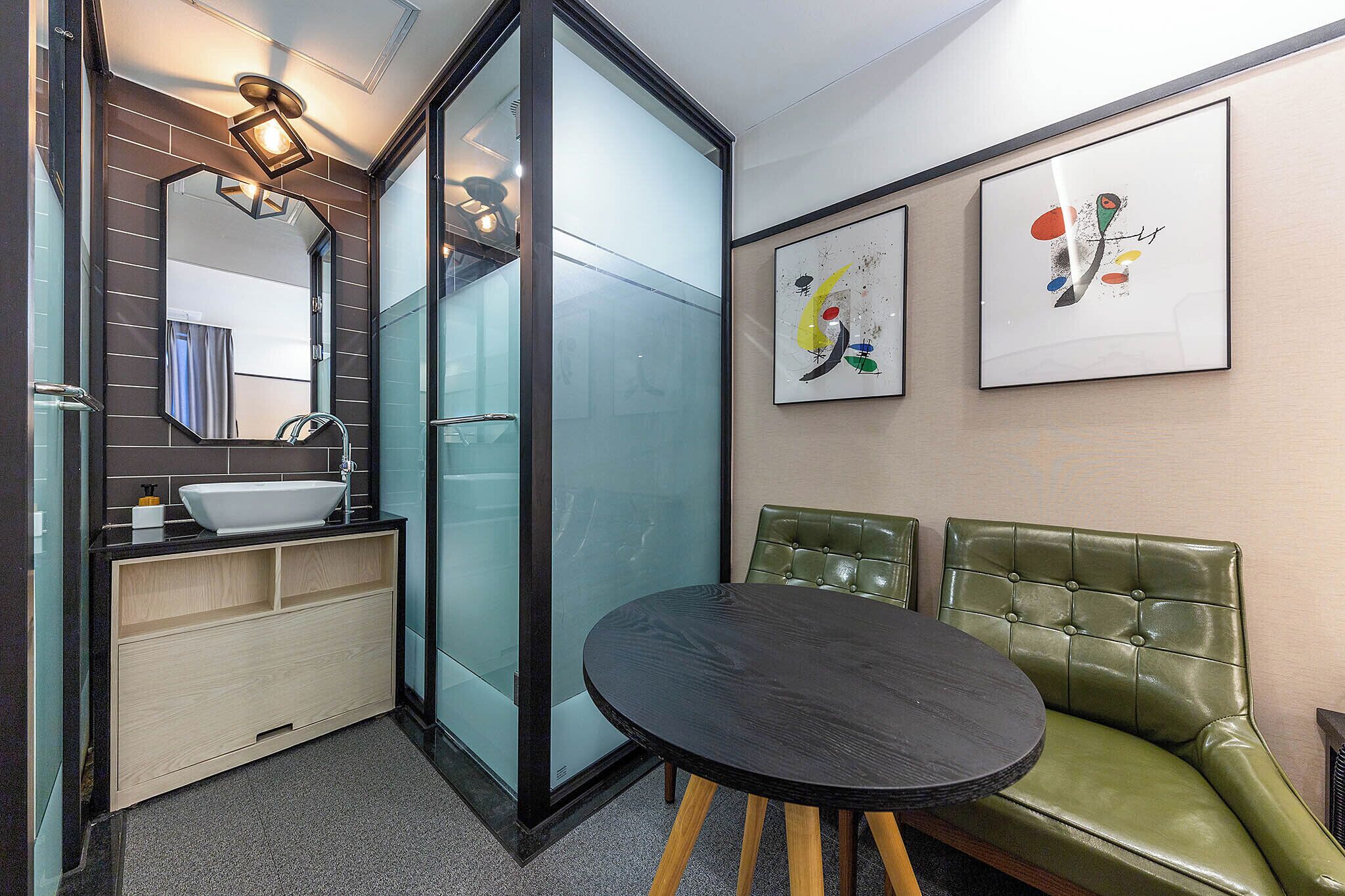 A modern bathroom with a glass shower enclosure, a sink, and a green leather bench.
