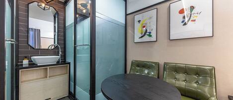 A modern bathroom with a glass shower enclosure, a sink, and a green leather bench.