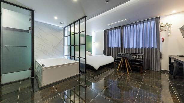 A modern hotel room with a large bed, a separate bathroom with a bathtub, a desk, and a chair. - Brown Dot Hotel Jinjuseong (Jinju)