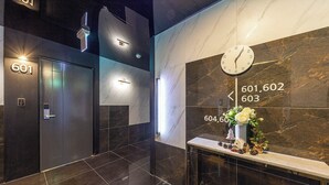 A modern lobby with a marble wall, a clock, and a reception desk with a vase of flowers. - Brown Dot Hotel Jinjuseong (Jinju)