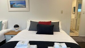A hotel room with a bed, two pillows, a nightstand with a lamp, and a framed picture on the wall.