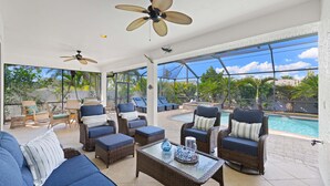 A spacious outdoor patio with wicker furniture, ceiling fans, and a view of a swimming pool. - Bonita Breeze | Prime Location | Screened Pool & Spa (Bonita Springs)