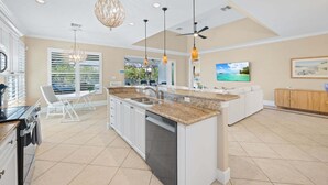 A spacious kitchen with a central island, white cabinetry, and a dining area with a view. - Bonita Breeze | Prime Location | Screened Pool & Spa (Bonita Springs)
