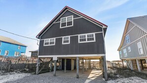 Et toetagers hus med en overdækket veranda, en indhegnet gårdhave og en klar himmel.