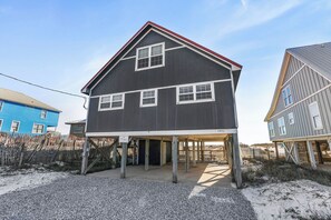 Ein zweigeschossiges Haus mit einer überdachten Veranda, einem eingezäunten Garten und blauem Himmel.